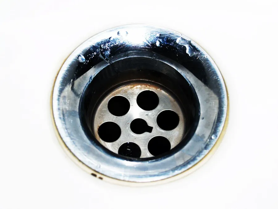A close-up of a kitchen sink drain and its metal strainer